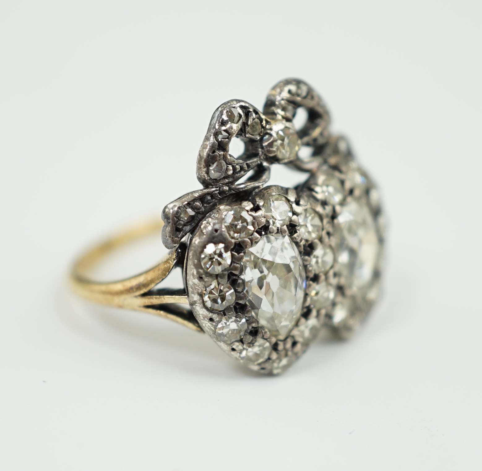 A 19th century gold, silver and diamond cluster set twin hearts ring, with ribbon bow surmounted